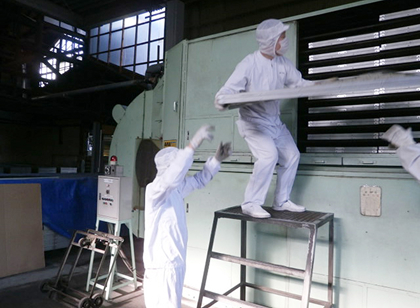 枠に並べた生地を乾燥機へ運ぶ従業員